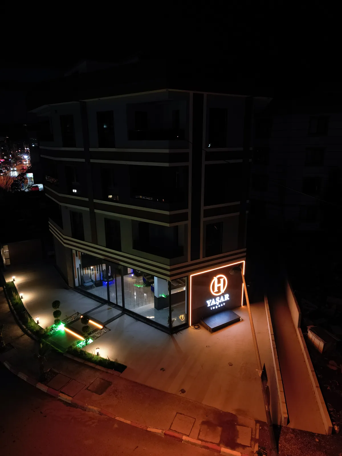 Ofis binası gece, cephe LED şeritleri ve ışıklı H YAŞAR İNŞAAT tabelası yanıyor